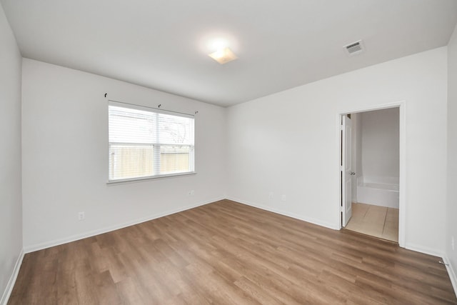 empty room with visible vents, baseboards, and wood finished floors