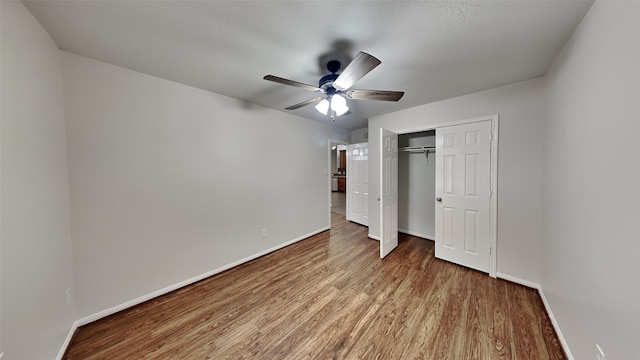 unfurnished bedroom featuring hardwood / wood-style flooring, ceiling fan, and a closet