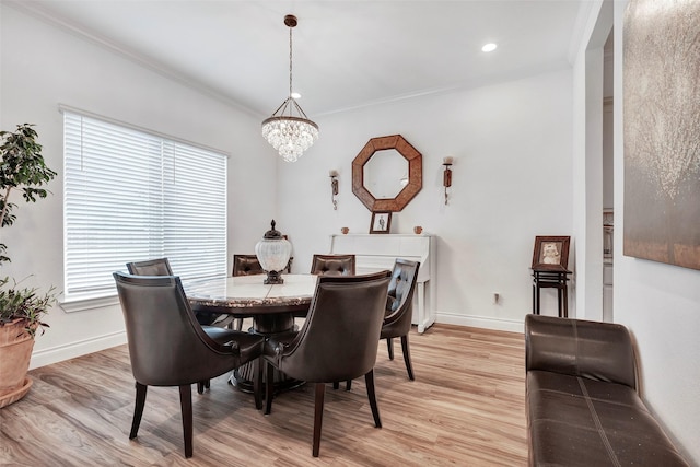 dining area featuring light wood-type flooring, a chandelier, and crown molding