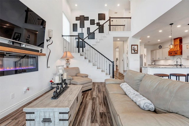 living room with sink, wood-type flooring, and a towering ceiling