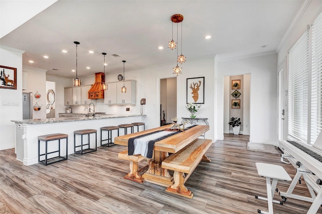 dining room featuring sink, ornamental molding, and light hardwood / wood-style floors