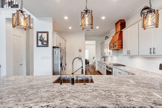 kitchen with appliances with stainless steel finishes, sink, hanging light fixtures, and white cabinets