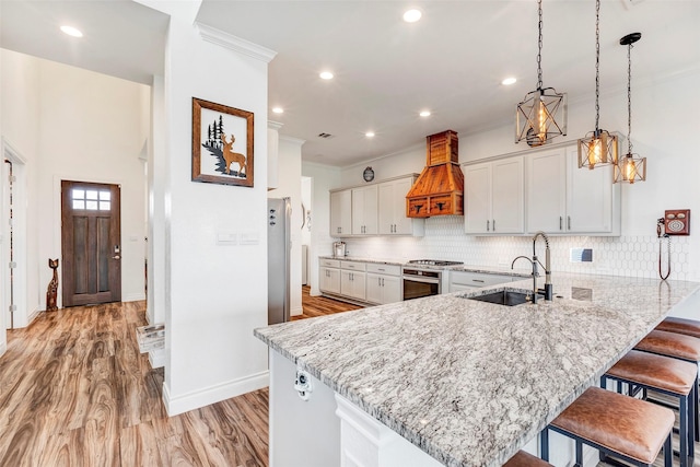 kitchen featuring premium range hood, pendant lighting, kitchen peninsula, white cabinets, and decorative backsplash