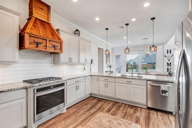 kitchen featuring sink, light hardwood / wood-style floors, stainless steel appliances, white cabinets, and hanging light fixtures