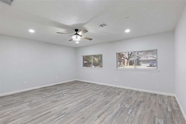 empty room featuring light hardwood / wood-style flooring, ceiling fan, and a textured ceiling