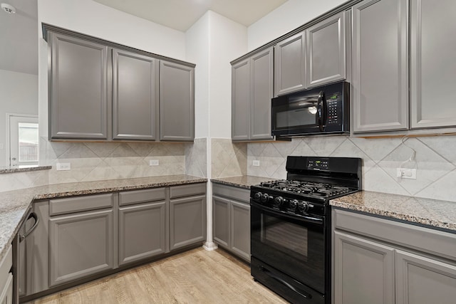 kitchen with gray cabinets, black appliances, and light stone counters