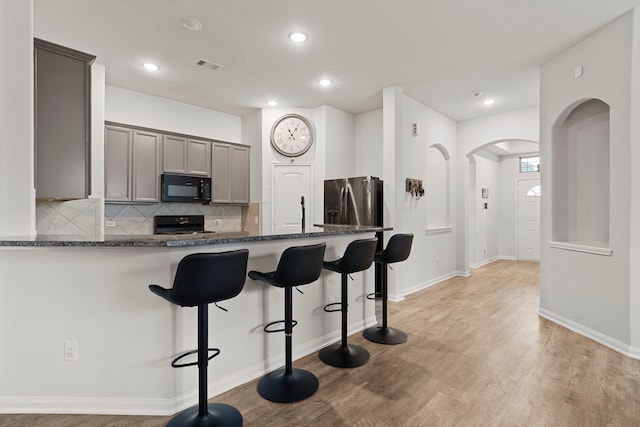 kitchen featuring range, gray cabinetry, light hardwood / wood-style floors, stainless steel fridge, and kitchen peninsula