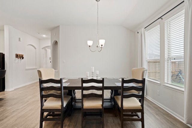 dining area featuring hardwood / wood-style flooring, a chandelier, and lofted ceiling