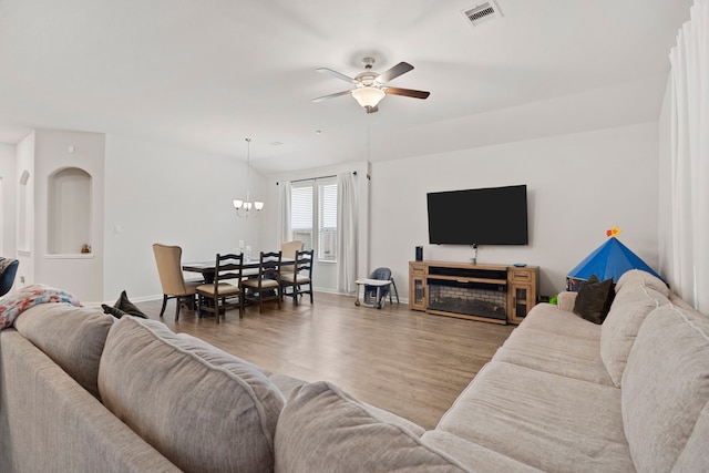 living room featuring a fireplace, ceiling fan with notable chandelier, and wood-type flooring