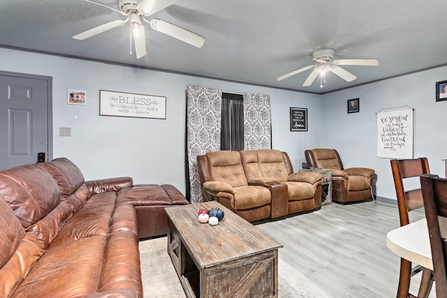 living room with ornamental molding, ceiling fan, light wood-type flooring, and a textured ceiling