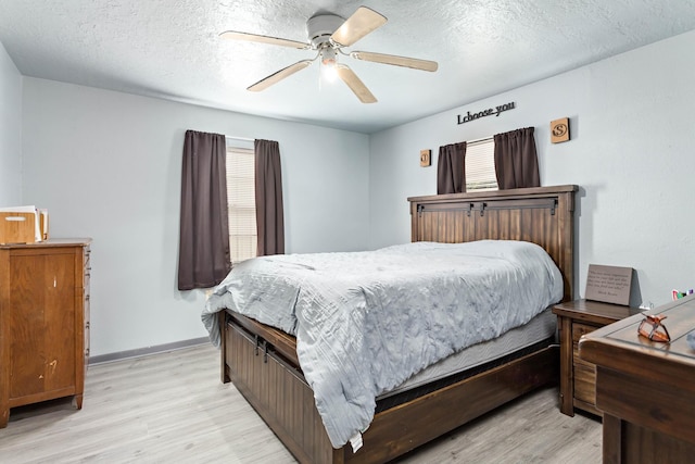 bedroom featuring ceiling fan, light wood-type flooring, and a textured ceiling