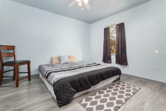 bedroom featuring ceiling fan, light wood-type flooring, and a textured ceiling