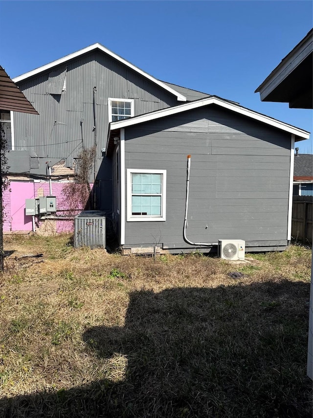 view of side of home featuring a yard, ac unit, and central AC