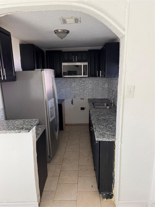 kitchen featuring light tile patterned flooring, stainless steel appliances, tasteful backsplash, and sink