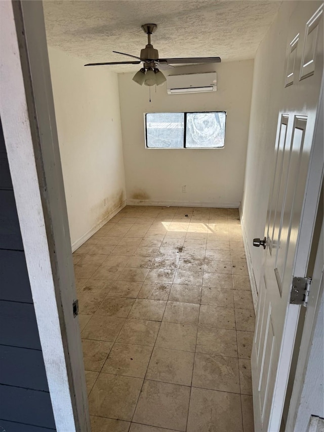 spare room featuring ceiling fan, a wall mounted AC, and a textured ceiling