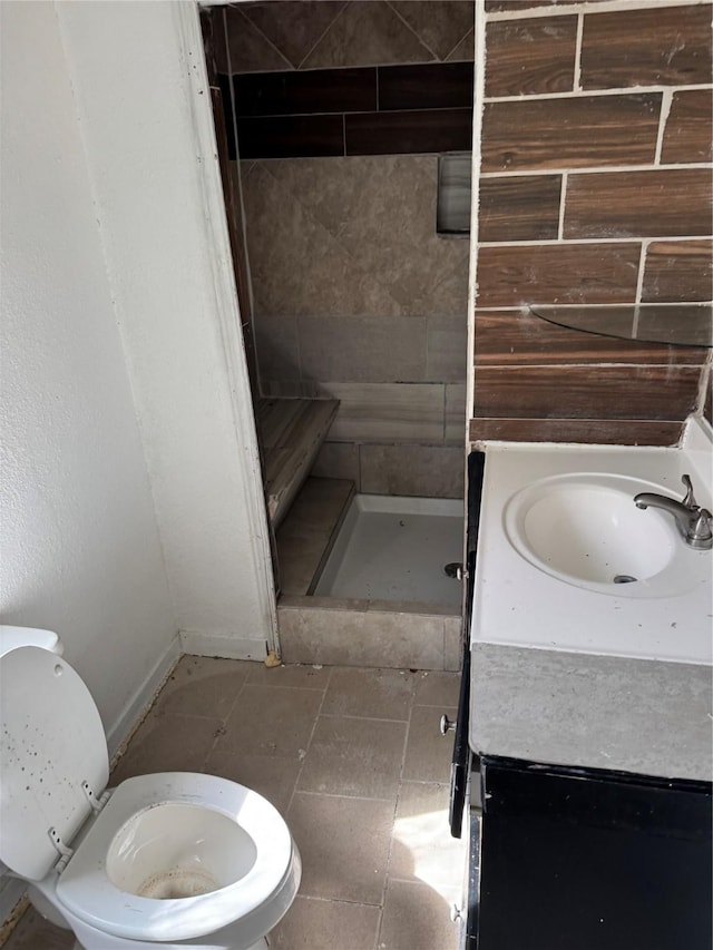 bathroom with toilet, vanity, and tiled shower