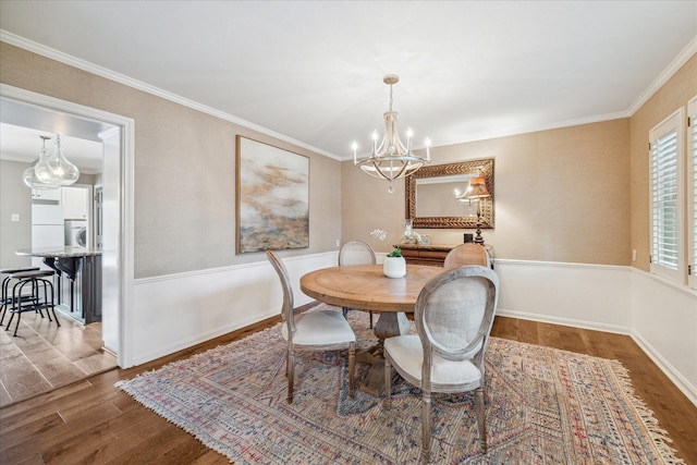 dining area featuring stacked washing maching and dryer, an inviting chandelier, crown molding, and hardwood / wood-style flooring