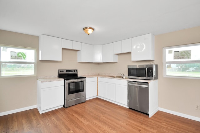 kitchen featuring sink, appliances with stainless steel finishes, white cabinetry, and light hardwood / wood-style floors