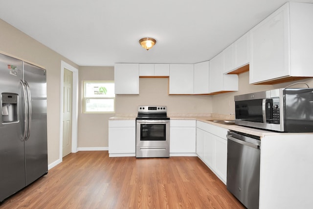 kitchen with light hardwood / wood-style flooring, stainless steel appliances, and white cabinets