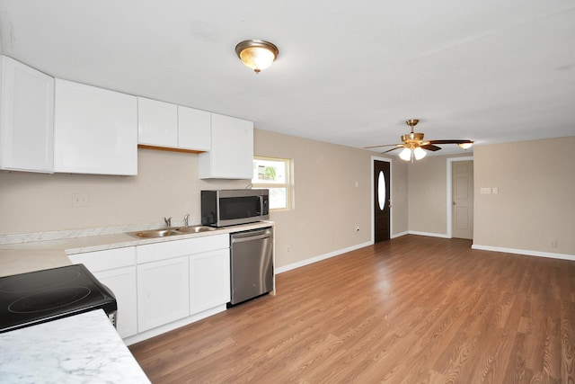 kitchen with sink, stainless steel appliances, white cabinets, and light wood-type flooring