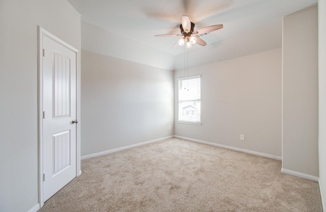 empty room with lofted ceiling, ceiling fan, and light colored carpet