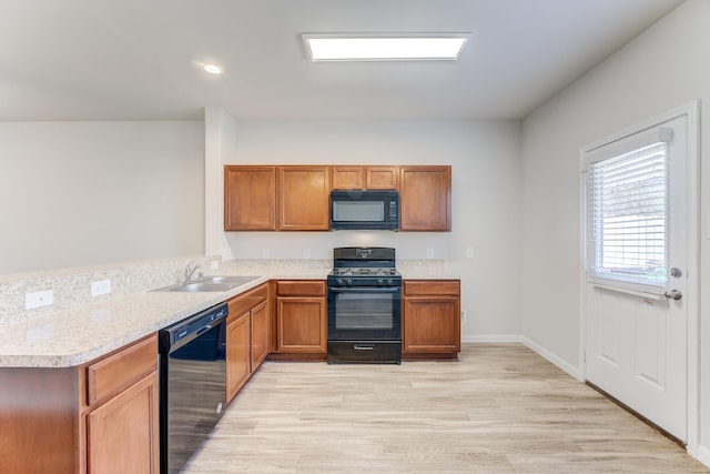 kitchen featuring light wood-type flooring, sink, black appliances, and kitchen peninsula