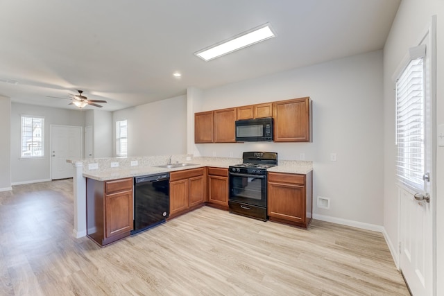 kitchen with sink, kitchen peninsula, black appliances, and light hardwood / wood-style floors