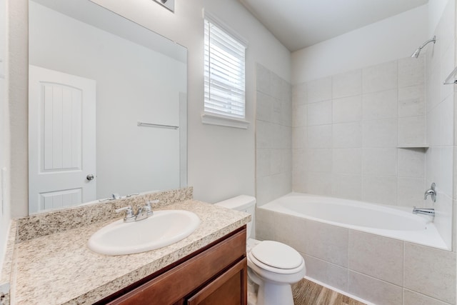 full bathroom with hardwood / wood-style floors, toilet, vanity, and tiled shower / bath