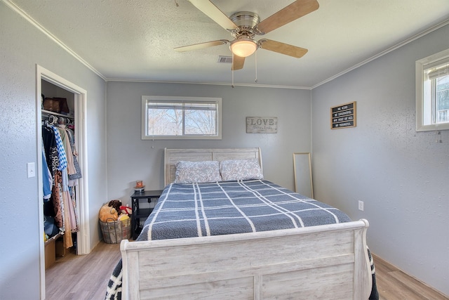 bedroom with light wood-type flooring, crown molding, and multiple windows