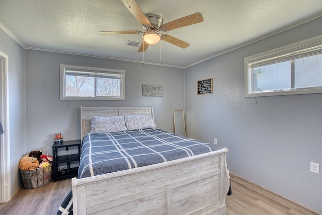 bedroom featuring crown molding, wood-type flooring, and a textured ceiling