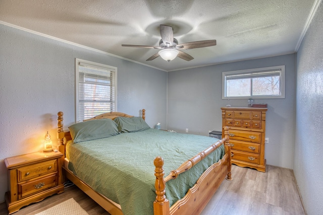 bedroom featuring light wood-type flooring, crown molding, and a textured ceiling