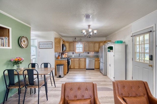 kitchen with appliances with stainless steel finishes, ornamental molding, light hardwood / wood-style floors, and a chandelier