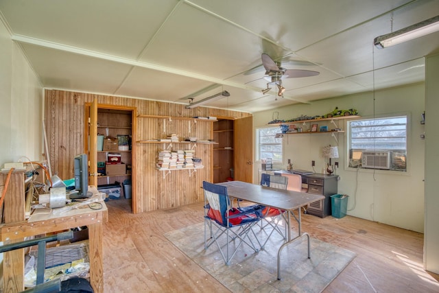 dining room featuring cooling unit, ceiling fan, light hardwood / wood-style flooring, and wooden walls