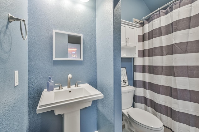 bathroom featuring toilet and a textured wall