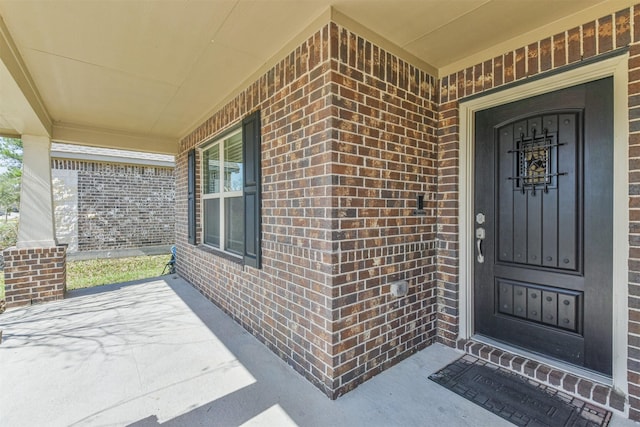 property entrance with brick siding and covered porch