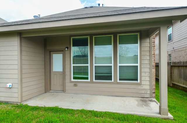 view of exterior entry featuring a yard and a patio area