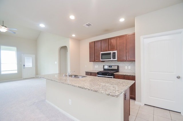 kitchen featuring appliances with stainless steel finishes, sink, tasteful backsplash, and a center island with sink