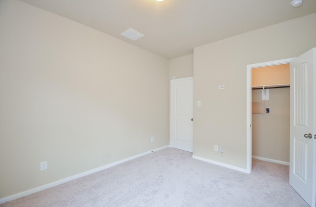 unfurnished bedroom with light carpet, a closet, and a spacious closet