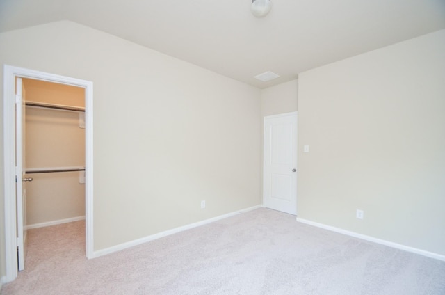 unfurnished bedroom featuring a closet, light colored carpet, and a walk in closet