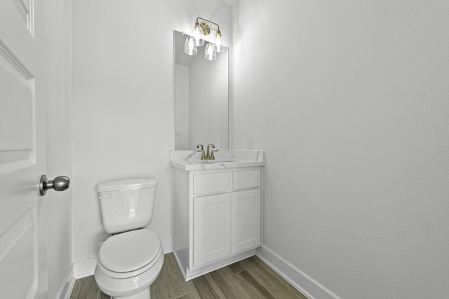 bathroom with toilet, hardwood / wood-style flooring, and vanity