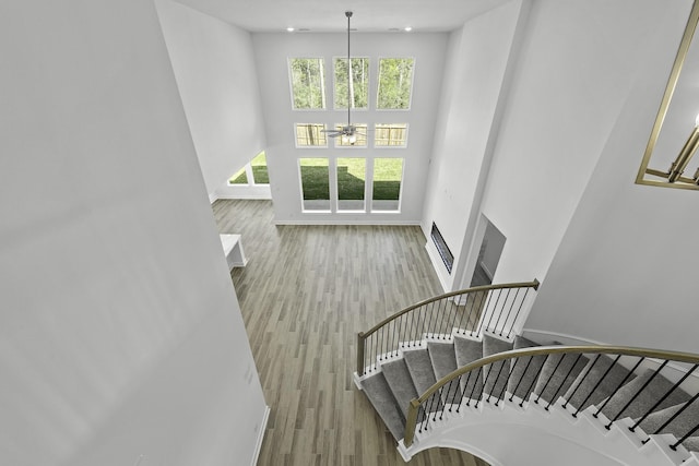 stairway featuring ceiling fan, a high ceiling, and wood-type flooring