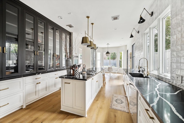 kitchen featuring light hardwood / wood-style flooring, hanging light fixtures, stainless steel appliances, a center island, and sink