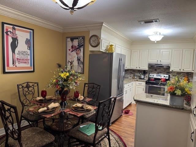 kitchen with white cabinets, light hardwood / wood-style floors, stainless steel appliances, and a textured ceiling