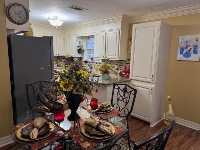 kitchen featuring white cabinets, dark hardwood / wood-style flooring, backsplash, and ornamental molding