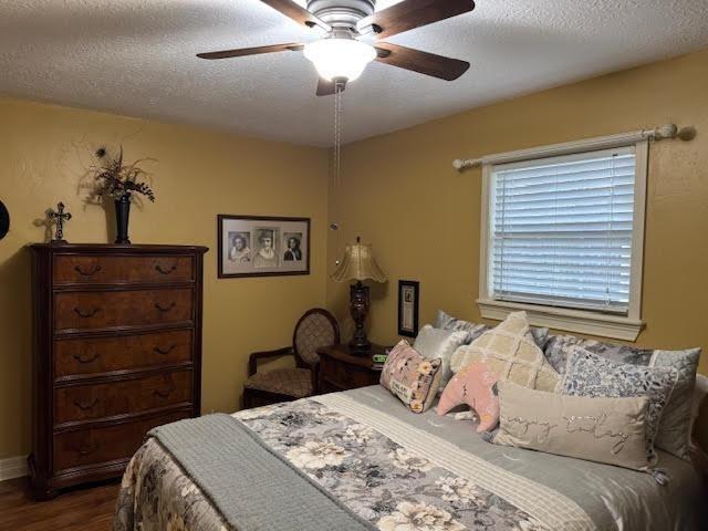 bedroom with a textured ceiling, ceiling fan, and wood-type flooring