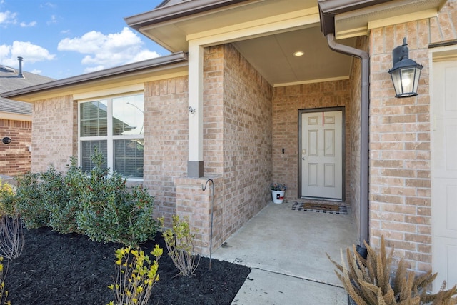 entrance to property featuring a garage and brick siding