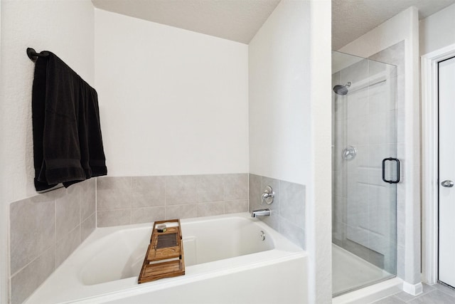 full bathroom featuring a shower stall, a textured ceiling, and a bath