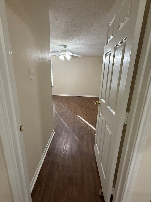 corridor with dark hardwood / wood-style floors and a textured ceiling