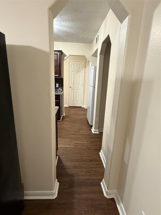 hallway featuring a textured ceiling and dark wood-type flooring