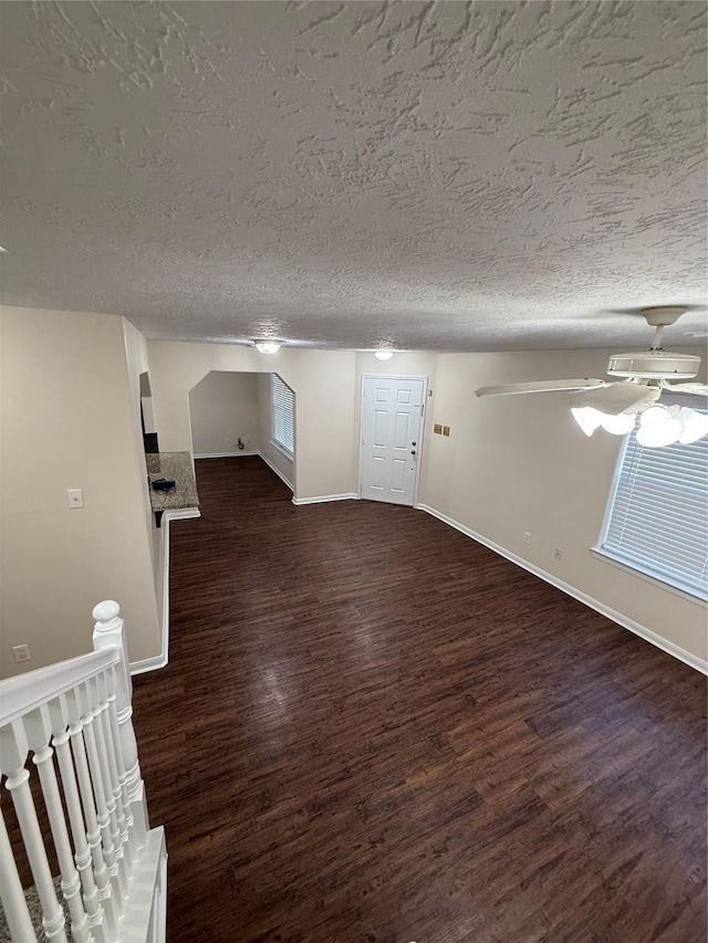 interior space featuring a textured ceiling, dark wood-type flooring, and ceiling fan